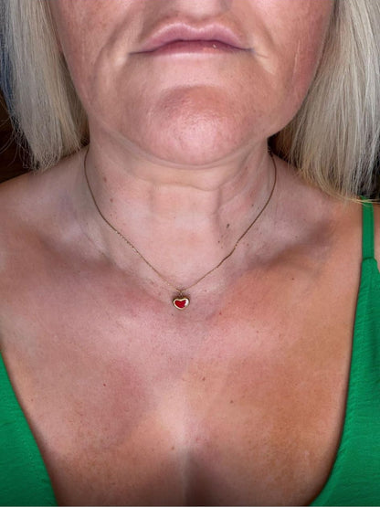 Person wearing a green top with a necklace featuring a red pendant.