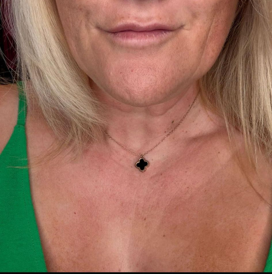 Close-up of a person with blonde hair and a green top, wearing a necklace.